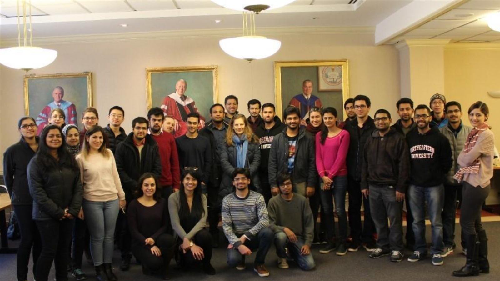 About forty chapter members standing together for a group photo in a formal room with portraits on the wall.